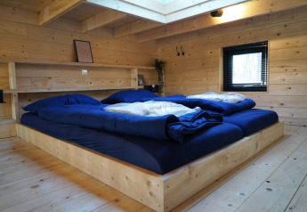 Schlafzimmer im Tiny House bei De Hooge Veluwe mit Holzverkleidung, großem Bett und Tageslicht.