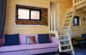 Interiør af en Tiny House-lodge ved De Hooge Veluwe i Holland med trævægge og en lyserød sofa.