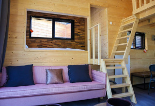 Interno della Tiny House a De Hooge Veluwe, Paesi Bassi, con pareti in legno e divano rosa.