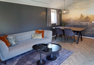 Salon moderne au lodge Velthorst, De Hooge Veluwe, Pays-Bas, avec canapé, table et fresque murale nature.