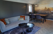 Moderne living in lodge Velthorst bij De Hooge Veluwe, Nederland, met zetel, eettafel en wanddecoratie.