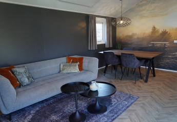 Salon moderne au lodge Velthorst, De Hooge Veluwe, Pays-Bas, avec canapé, table et fresque murale nature.