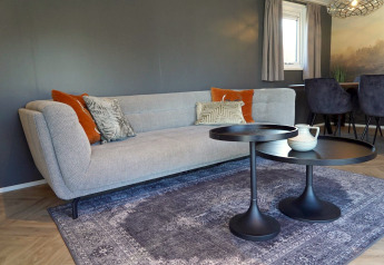 Modernes Wohnzimmer in der Velthorst-Lodge bei De Hooge Veluwe, Niederlande mit Sofa und Tischen.