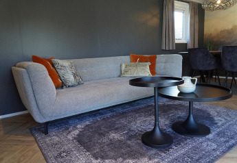 Modern living room at Velthorst lodge in De Hooge Veluwe, Netherlands, with sofa, tables, and cushions.