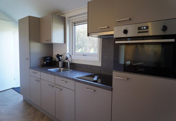 Modern kitchen interior of a Velthorst lodge at De Hooge Veluwe, Netherlands, showing oven and window.