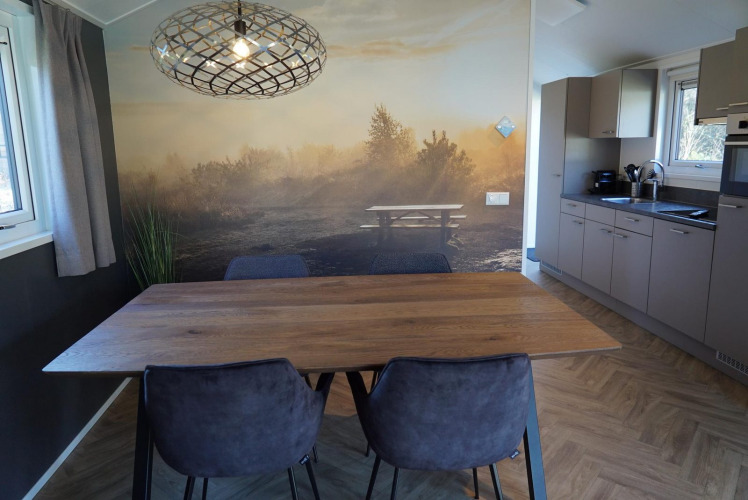 Comedor en la cabaña Velthorst de De Hooge Veluwe, Países Bajos, con mural natural y cocina moderna.