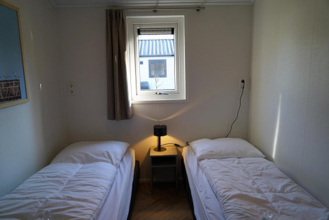 Dos camas individuales con ropa blanca en un cuarto sencillo del lodge Velthorst en De Hooge Veluwe, Países Bajos.