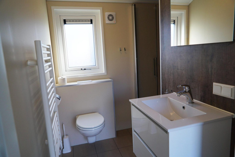 Baño moderno en la cabaña Velthorst en De Hooge Veluwe, Países Bajos, con inodoro, lavabo y ducha.