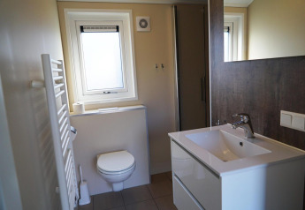 Salle de bain moderne au lodge Velthorst à De Hooge Veluwe, Pays-Bas, avec toilettes, lavabo et douche.