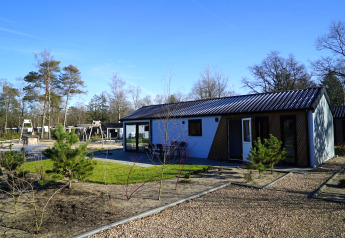 Moderne Velthorst-Lodge im Park De Hooge Veluwe in den Niederlanden, umgeben von Natur und Spielplatz.