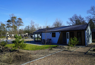 Lodge Velthorst moderne à De Hooge Veluwe aux Pays-Bas entouré d’arbres et d’une aire de jeux.