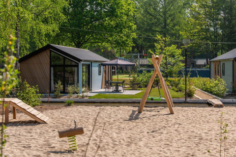 Modernos lodges en Velthorst De Hooge Veluwe, Países Bajos, con área de juegos y vegetación.
