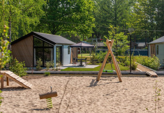 Cabanes modernes à Velthorst De Hooge Veluwe, Pays-Bas, avec aire de jeux et espace vert.