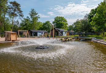 Outdoor view of Velthorst lodge at De Hooge Veluwe, Netherlands, featuring a fountain and scenic grounds.