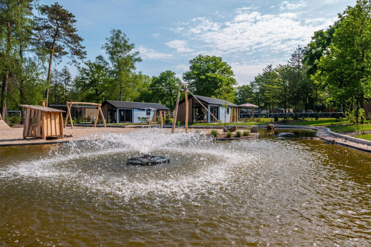 Vista exterior del lodge Velthorst en De Hooge Veluwe, Países Bajos, con fuente y entorno natural bonito.