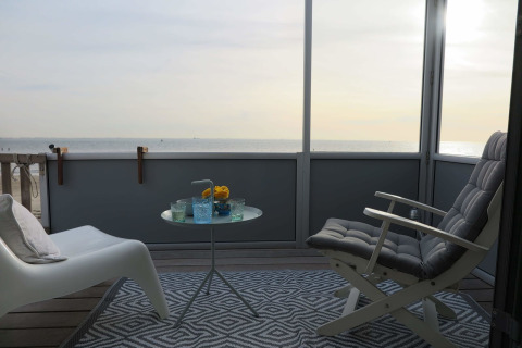 Vista del balcón en Beach house 'Dishoek 60', Zeeland, Países Bajos, con el mar al fondo y asientos cómodos.