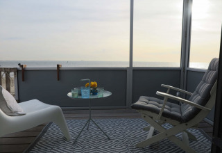 Vista del balcón en Beach house 'Dishoek 60', Zeeland, Países Bajos, con el mar al fondo y asientos cómodos.