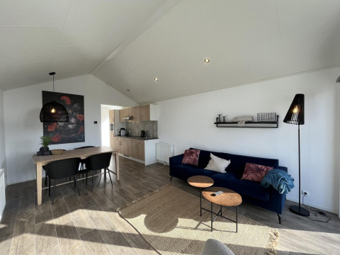 Soggiorno luminoso alla Forest Lodge di De Hooge Veluwe, Paesi Bassi, con cucina a vista e divano blu.