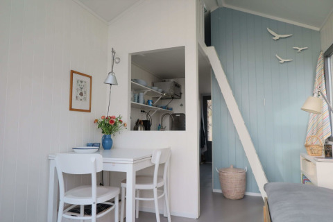 Interior luminoso y acogedor en Beach house 'Dishoek 60' con mesa de comedor y escalera, Dishoek, Países Bajos.