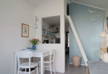 Interno luminoso e accogliente al Beach house 'Dishoek 60' con tavolo e scala a soppalco, Dishoek, Paesi Bassi.