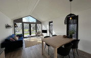 Moderne opholdsstue i Forest Lodge ved De Hooge Veluwe, Holland, med store vinduer og stilfuld indretning.