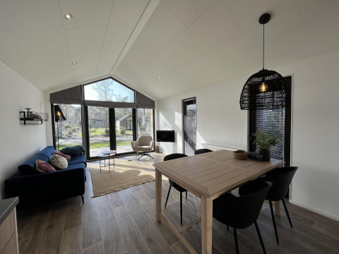 Moderne leefruimte in Forest Lodge bij De Hooge Veluwe, Nederland, met grote ramen en stijlvol interieur.