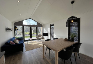 Moderne opholdsstue i Forest Lodge ved De Hooge Veluwe, Holland, med store vinduer og stilfuld indretning.