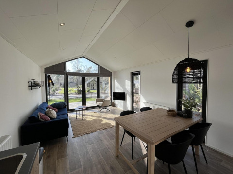 Modernes Wohnzimmer in der Forest Lodge bei De Hooge Veluwe mit großen Fenstern und viel Licht.