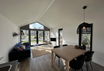 Modernes Wohnzimmer in der Forest Lodge bei De Hooge Veluwe mit großen Fenstern und viel Licht.