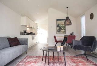 Soggiorno e cucina moderni nella Forest Lodge a De Hooge Veluwe, Paesi Bassi, con arredo elegante e luminoso.