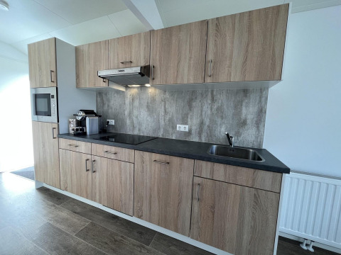 Cucina moderna presso Forest Lodge a De Hooge Veluwe, Paesi Bassi, con mobili in legno e elettrodomestici.