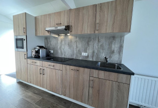 Moderne keuken in Forest Lodge bij De Hooge Veluwe in Nederland, met houten kasten en inbouwtoestellen.