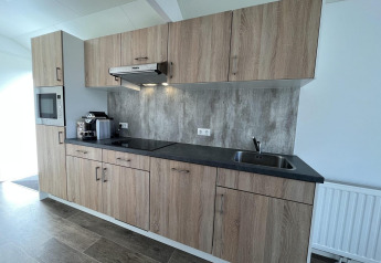 Moderne keuken in Forest Lodge bij De Hooge Veluwe, Nederland, met houten kasten en apparatuur.