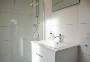 Baño moderno en Forest Lodge de De Hooge Veluwe, Países Bajos, con ducha, lavabo y espejo.