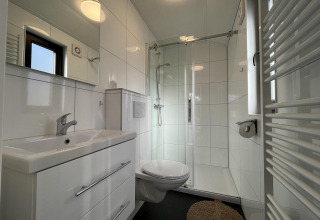 Bagno moderno al Forest Lodge di De Hooge Veluwe, Paesi Bassi, con doccia e arredi bianchi lucidi.