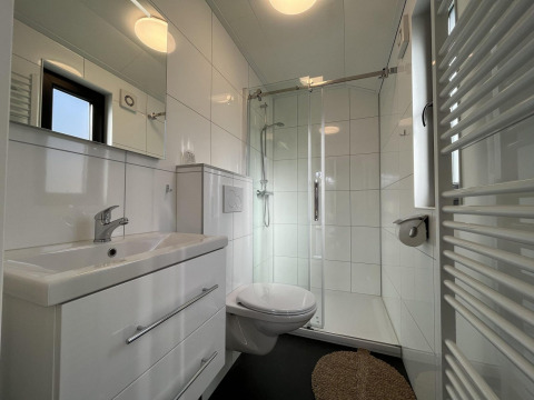 Moderne badeværelse i Forest Lodge ved De Hooge Veluwe, Holland, med bruseniche og hvidt interiør.