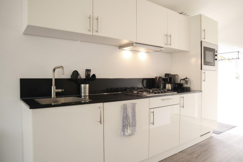 Moderne weiße Küche mit schwarzen Arbeitsplatten in der Forest Lodge bei De Hooge Veluwe, Niederlande.