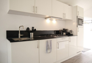 Moderne weiße Küche mit schwarzen Arbeitsplatten in der Forest Lodge bei De Hooge Veluwe, Niederlande.