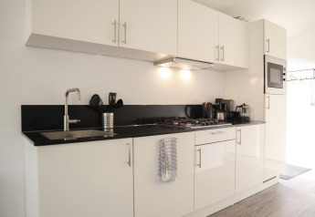 Moderne weiße Küche mit schwarzen Arbeitsplatten in der Forest Lodge bei De Hooge Veluwe, Niederlande.