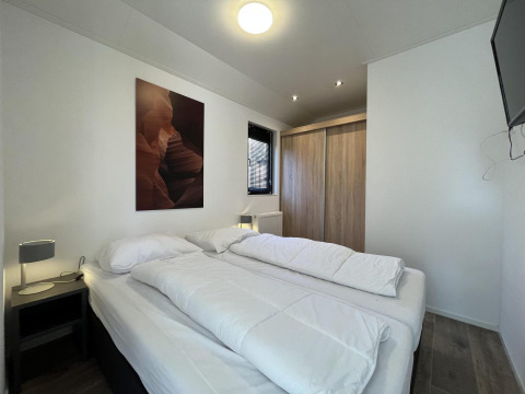 Schlafzimmer in der Forest Lodge bei De Hooge Veluwe, Niederlande, mit Doppelbett und Kleiderschrank.