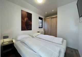 Schlafzimmer in der Forest Lodge bei De Hooge Veluwe, Niederlande, mit Doppelbett und Kleiderschrank.