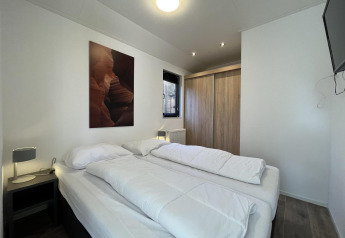 Schlafzimmer in der Forest Lodge bei De Hooge Veluwe, Niederlande, mit Doppelbett und Kleiderschrank.