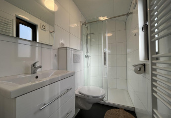 Modernes Badezimmer mit Dusche, Wandtoilette und Waschbecken in der Forest Lodge, De Hooge Veluwe, Niederlande.