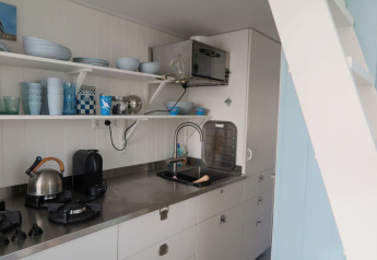 Cucina moderna presso Beach house 'Dishoek 60' con scaffali aperti e piano in acciaio a Zeeland, Olanda.