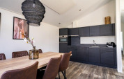 Moderne lodgekeuken en eetruimte met zwarte kasten, houten tafel, lederen stoelen en decoratie.
