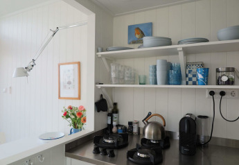 Cozy Beach house kitchen at Dishoek 60 with open shelves, gas stove, blue dishware, and coffee maker.