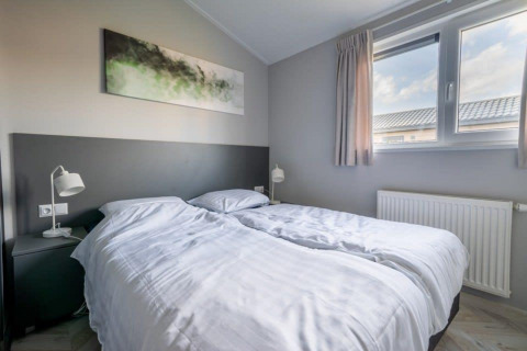 Moderne lodge-slaapkamer met twee aparte bedden, groot raam, nachtkastjes en moderne muurschildering.