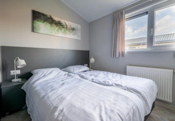 Dormitorio de lodge moderno con dos camas individuales, ventana grande, mesitas y arte en la pared.