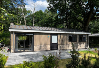 Lodge Hackfort 6 bij De Hooge Veluwe in Nederland, omringd door bomen en tuin in zonnig weer.