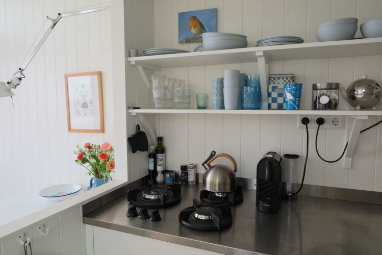 Helles Strandhaus-Küche Dishoek 60 mit offenen Regalen, Gasherd, Wasserkocher und Kaffeemaschine.